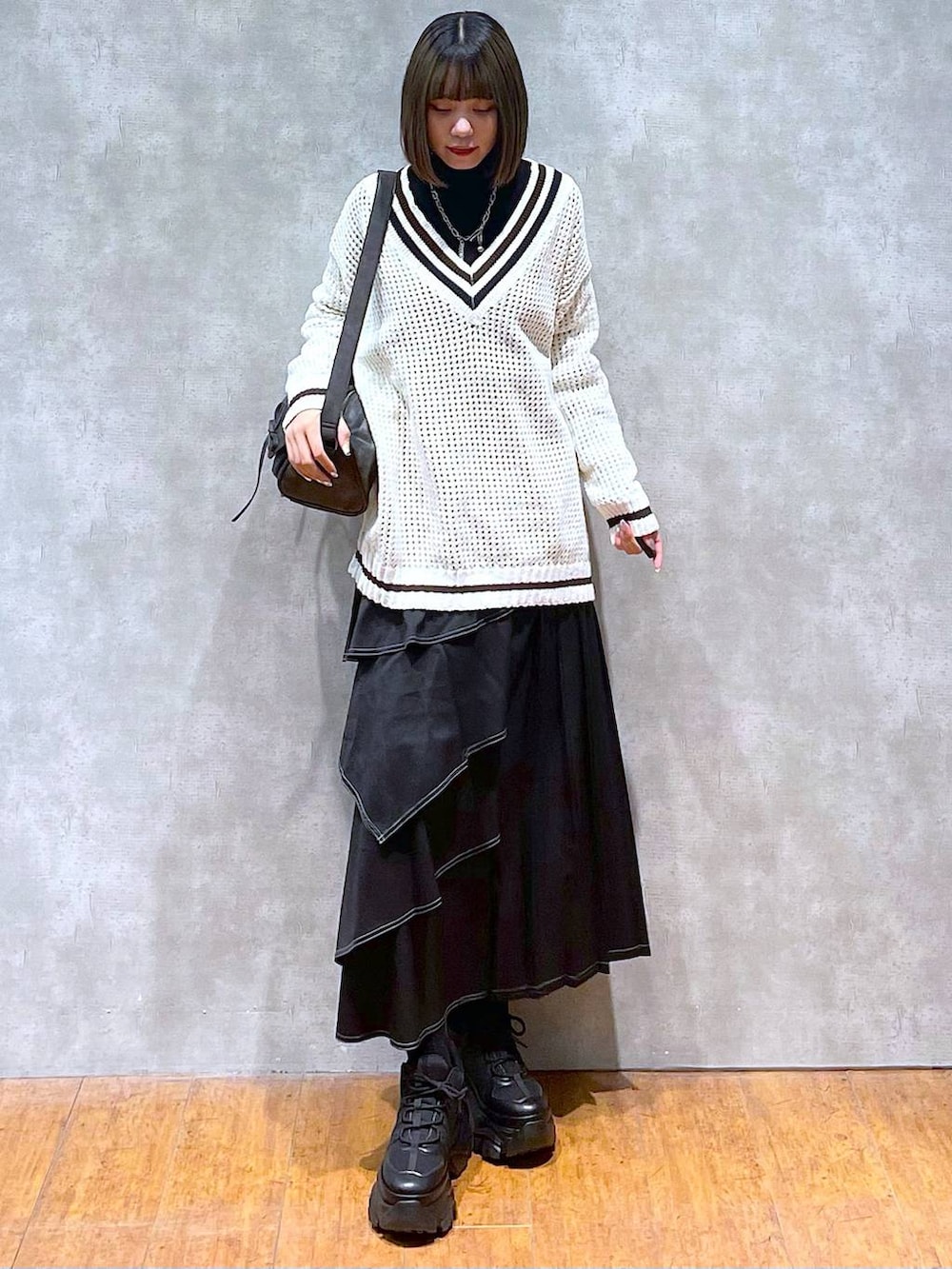 ブラック系のスニーカー、ブラック系のニット/セーター、ブラック系のショルダーバッグを着用したレディースの秋コーディネートの2枚目の写真