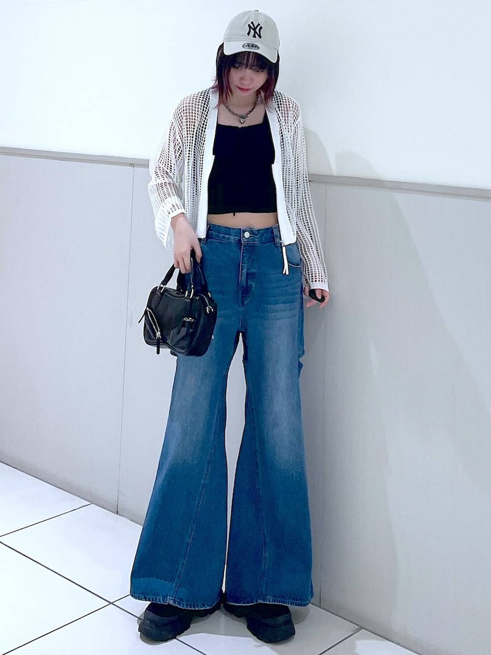 ホワイト系のカーディガン/ボレロ、ブラック系のタンクトップ、ブルー系のデニムパンツを着用したレディースの春コーディネートの2枚目の写真