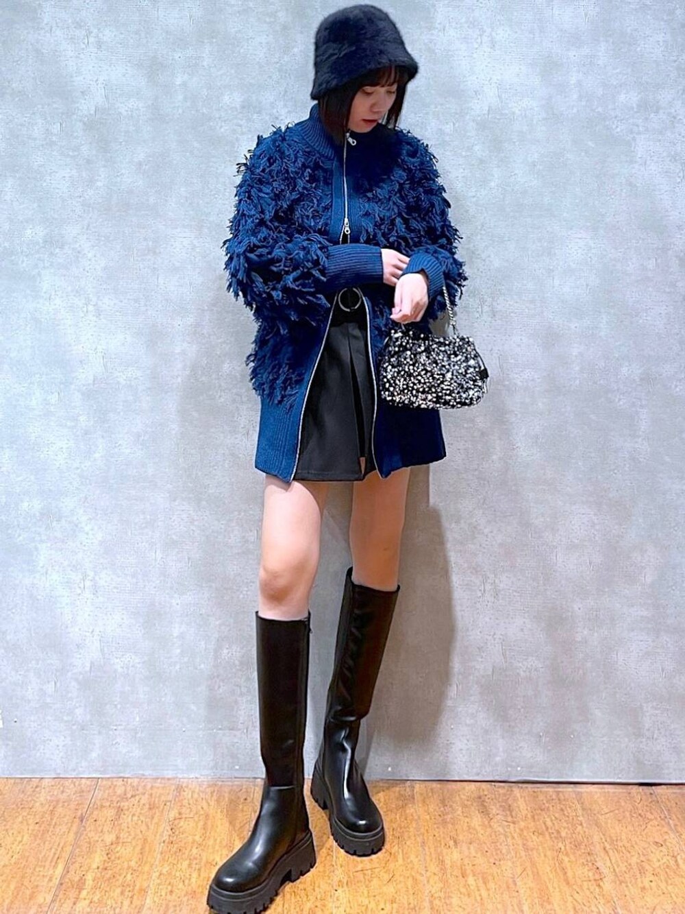 ブラック系のブーツ、ブラック系のニット/セーター、シルバー系のショルダーバッグを着用したレディースの冬コーディネートの2枚目の写真