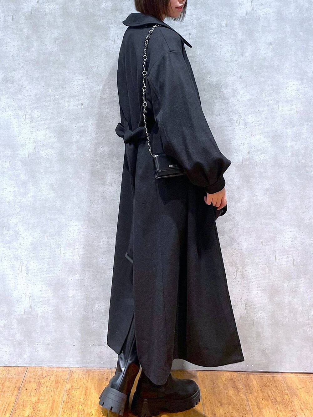 ブラック系のスカート、ブラック系のチェスターコート、ブラック系のブーツを着用したレディースの冬コーディネートの3枚目の写真