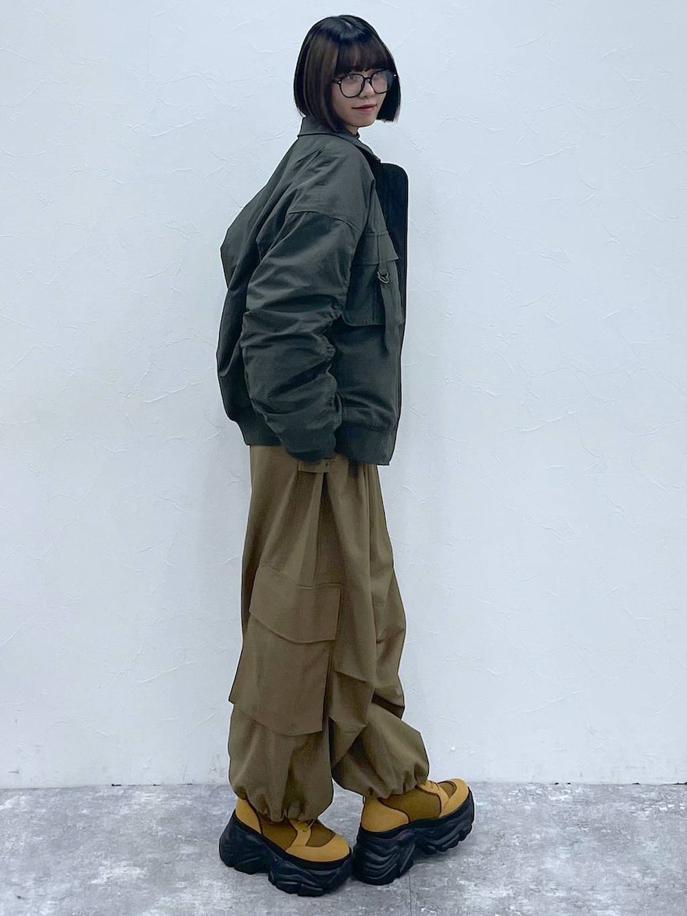 グレー系のネクタイ、ブラウン系のブーツ、グリーン系のブルゾンを着用したレディースの秋コーディネートの4枚目の写真