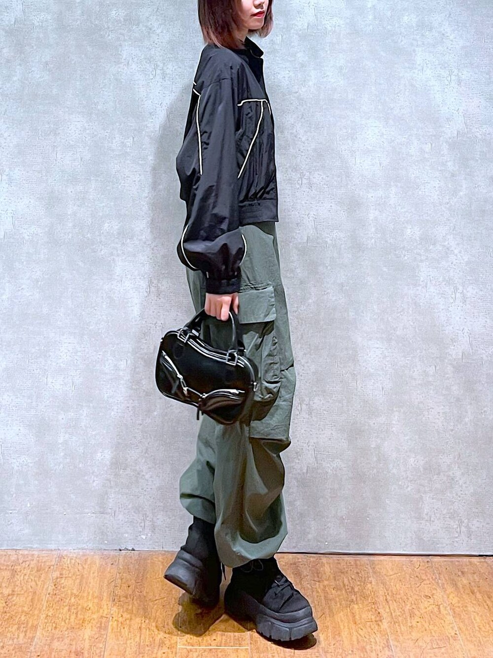 ブラック系のブルゾン、ホワイト系のTシャツ/カットソー、グリーン系のカーゴパンツを着用したレディースの春コーディネートの4枚目の写真