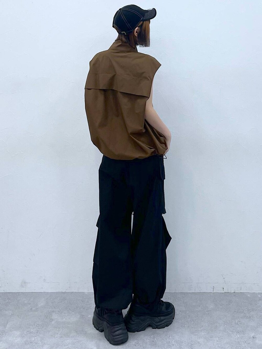 ブラック系のスニーカー、ブラック系のカーゴパンツ、ブラウン系のベストを着用したレディースの夏コーディネートの5枚目の写真