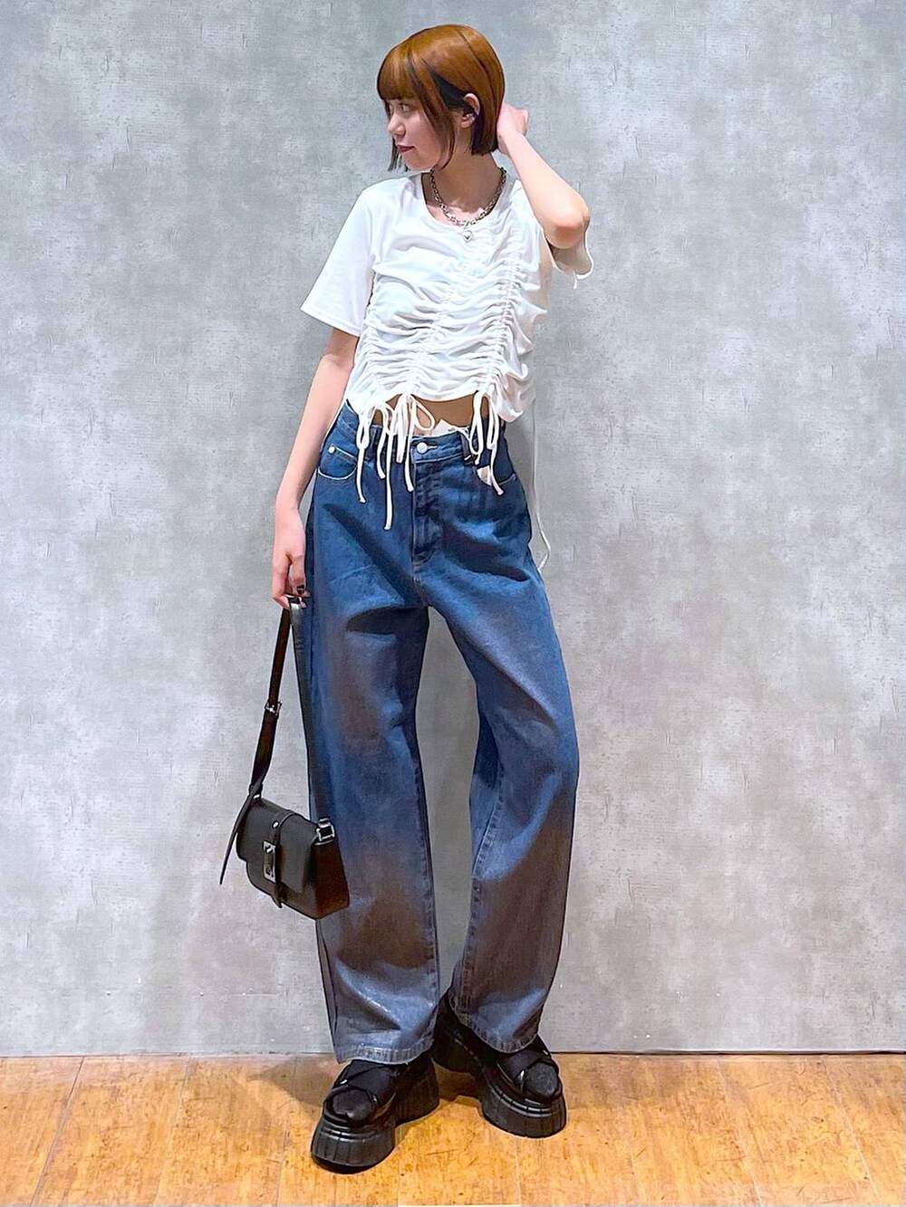 ブラック系のスニーカー、ブラック系のハンドバッグ、ホワイト系のTシャツ/カットソーを着用したレディースの夏コーディネートの2枚目の写真