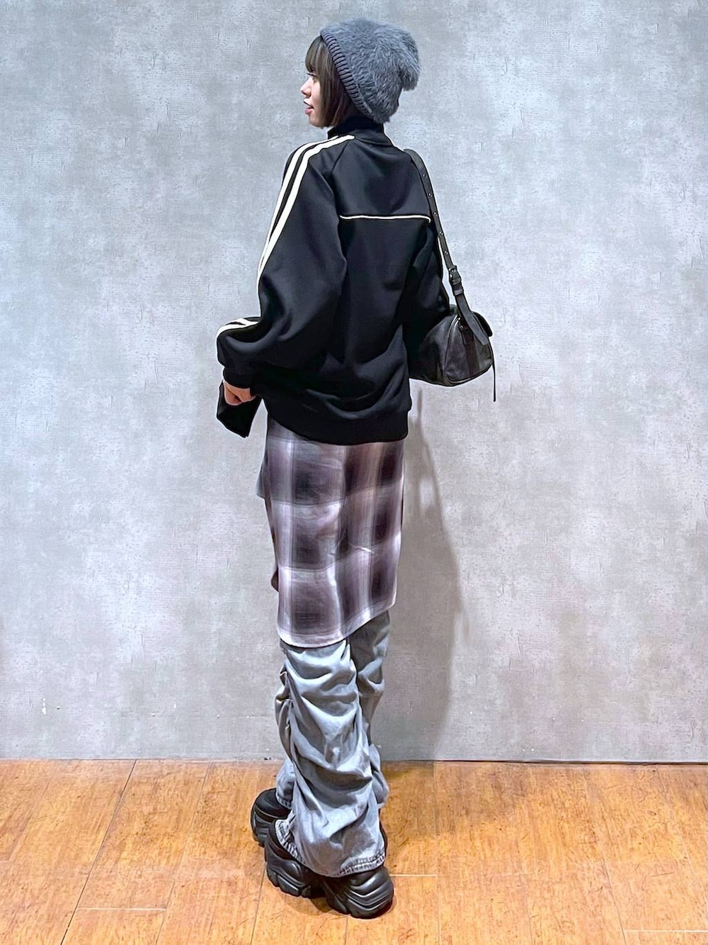 ブラック系のスニーカー、ブラック系のショルダーバッグ、ブルー系のデニムパンツを着用したレディースの秋コーディネートの3枚目の写真