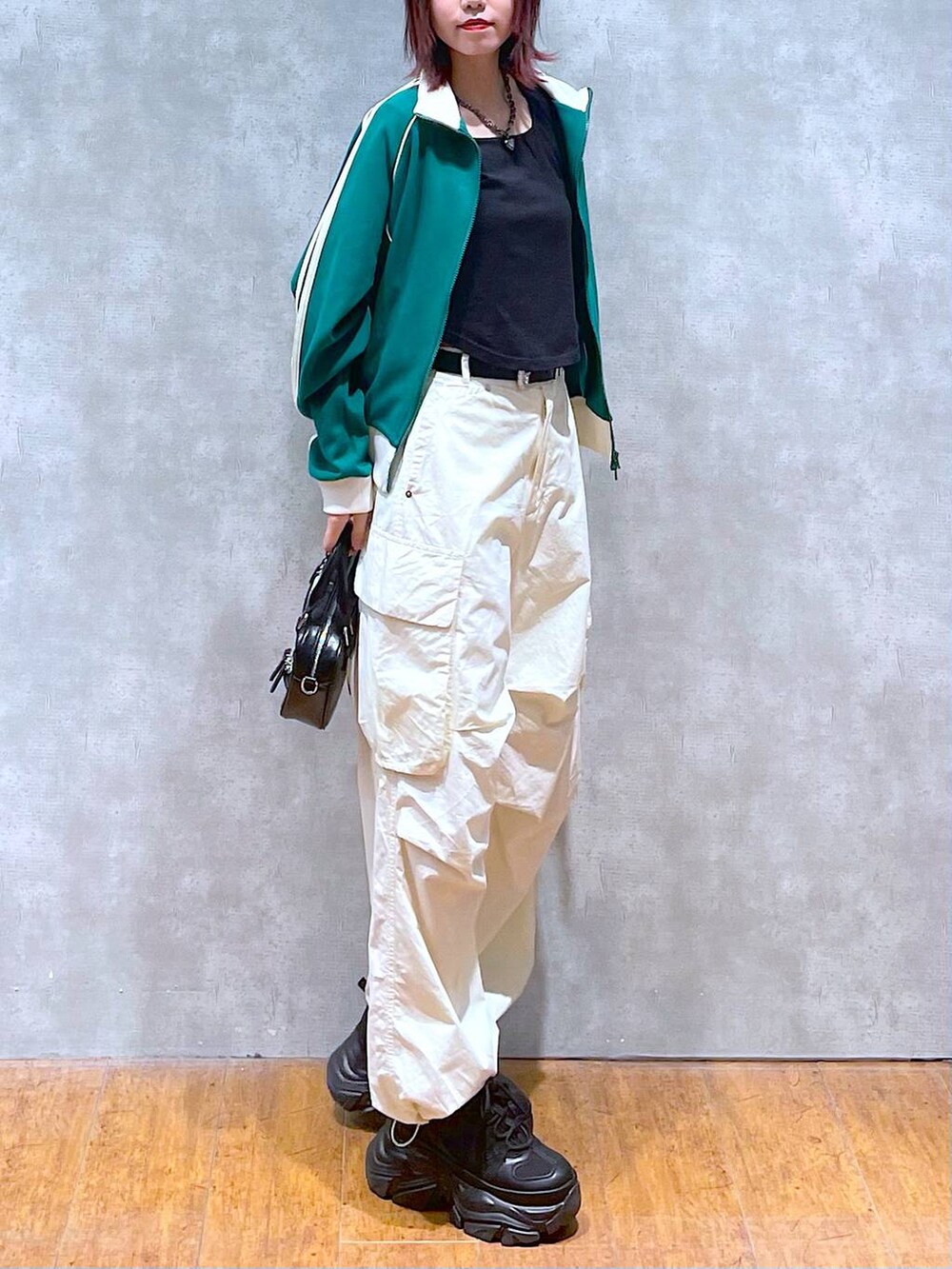 グリーン系のセットアップ、ブラック系のボストンバッグ、ホワイト系のカーゴパンツを着用したレディースの春コーディネートの5枚目の写真