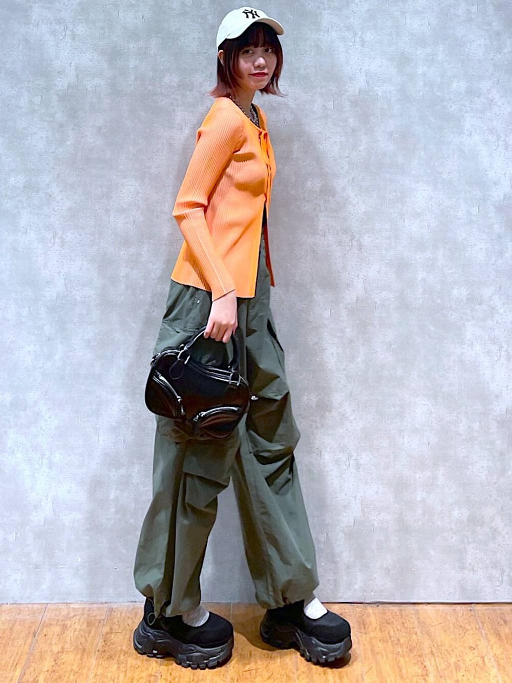 オレンジ系のニット/セーター、ブラック系のタンクトップ、ブラック系のボストンバッグを着用したレディースの春コーディネートの3枚目の写真