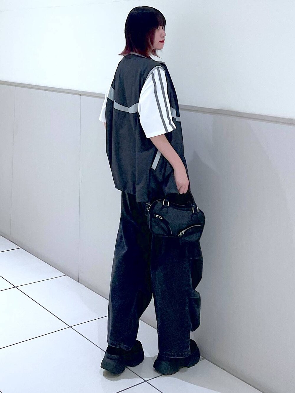 グレー系のベスト、ブラック系のデニムパンツ、ホワイト系のTシャツ/カットソーを着用したレディースの春コーディネートの4枚目の写真