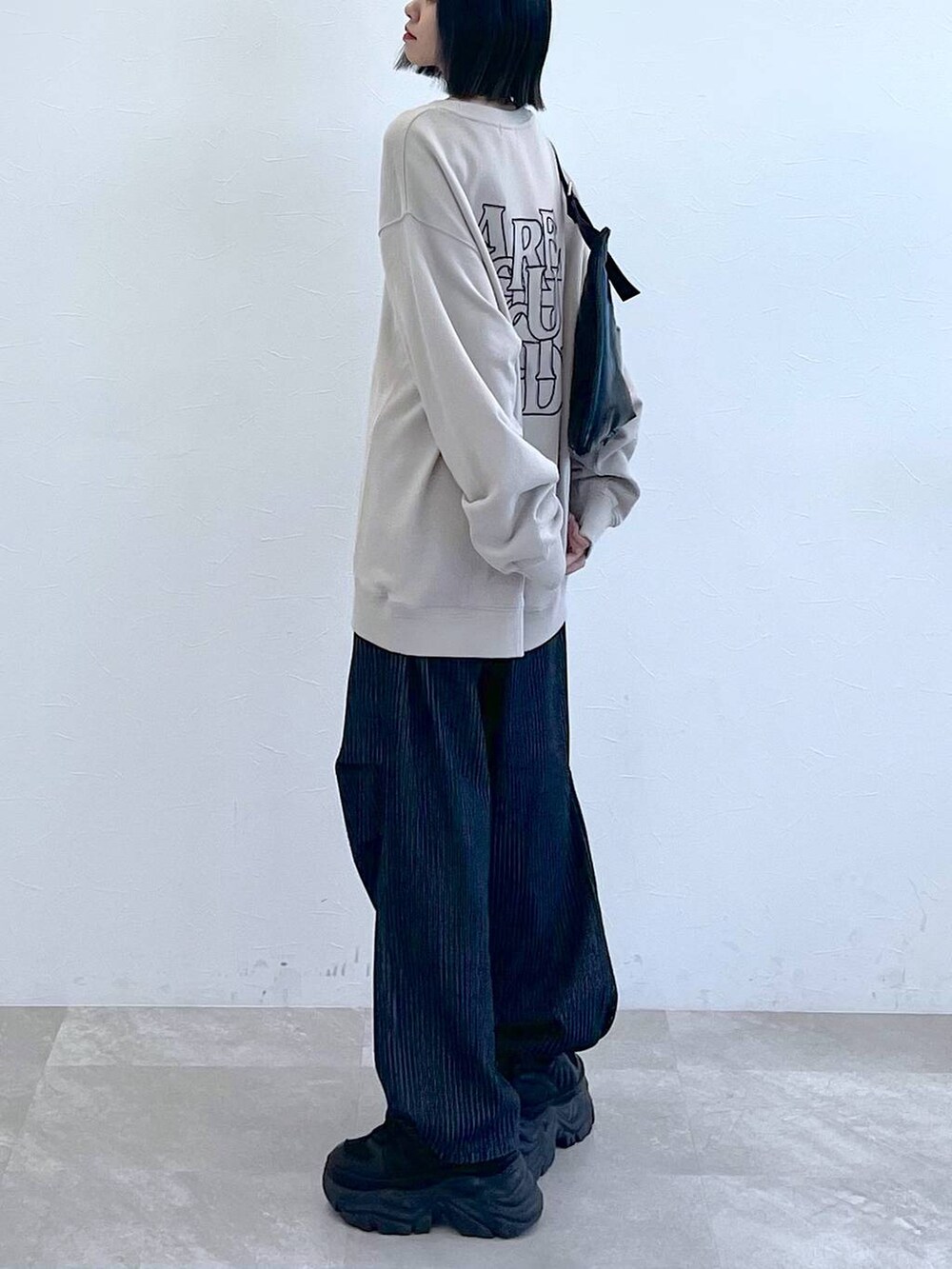 ブラック系のスニーカー、ブラック系のショルダーバッグ、ブラック系のデニムパンツを着用したレディースの秋コーディネートの3枚目の写真