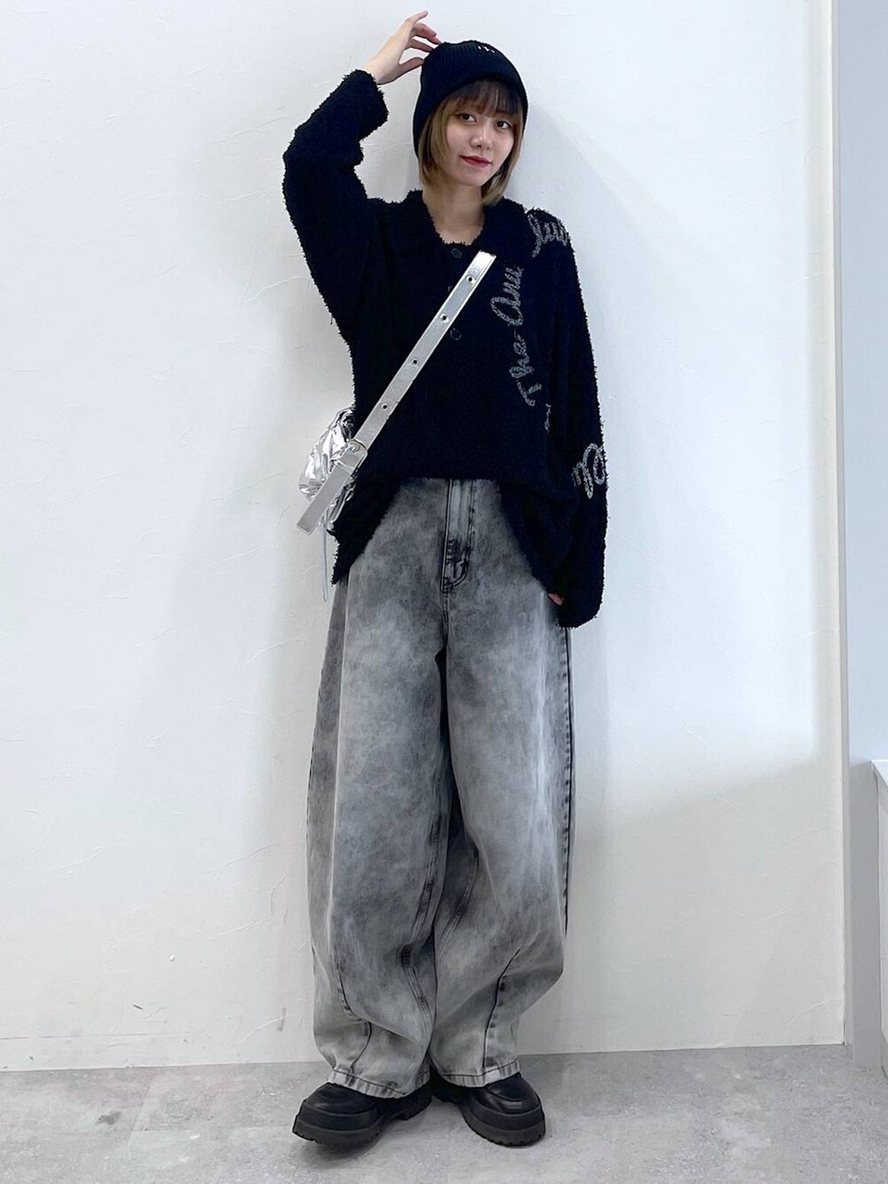 シルバー系のショルダーバッグ、ブラック系のブーツ、ブラック系のデニムパンツを着用したレディースの冬コーディネートの2枚目の写真