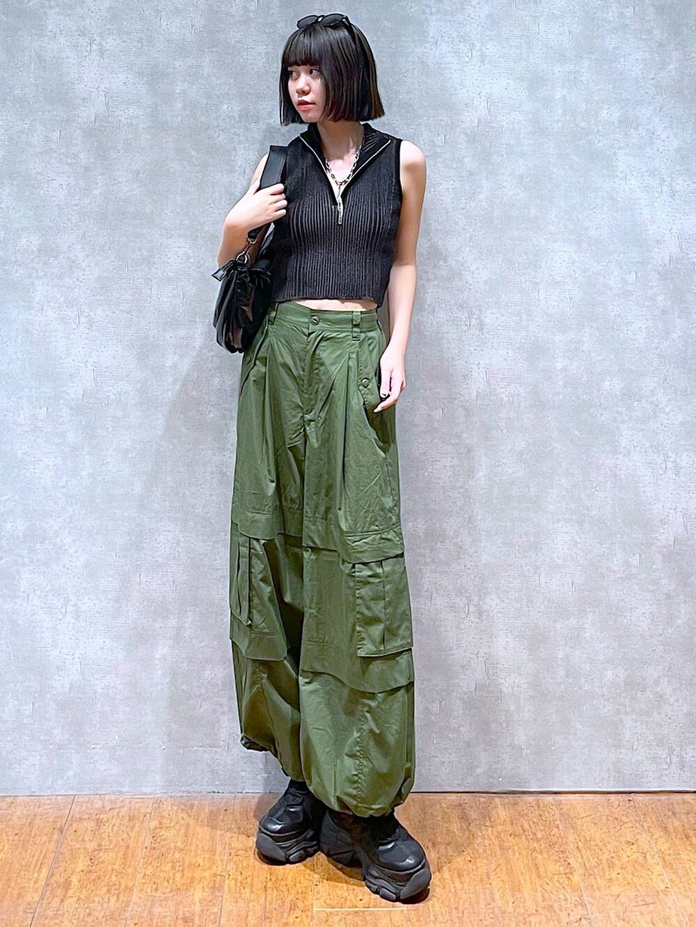 ブラック系のスニーカー、ブラック系のニット/セーター、グリーン系のその他パンツを着用したレディースの夏コーディネートの3枚目の写真