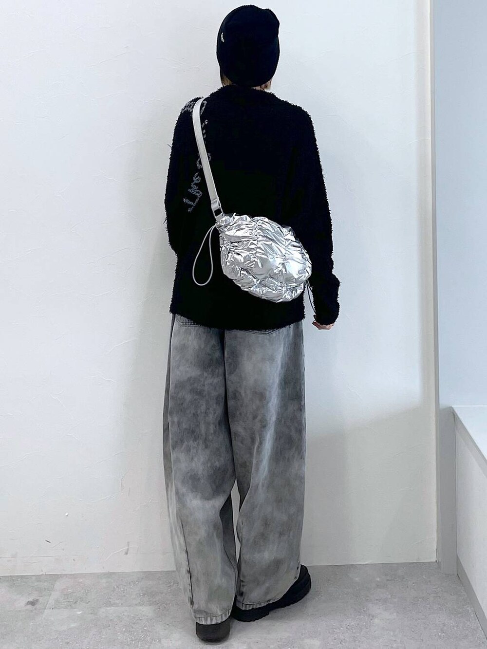 シルバー系のショルダーバッグ、ブラック系のブーツ、ブラック系のデニムパンツを着用したレディースの冬コーディネートの8枚目の写真