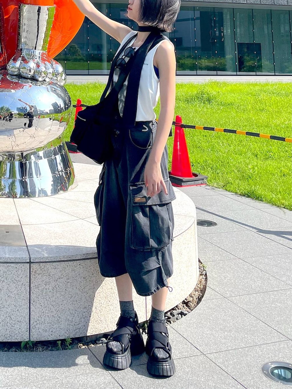 ブラック系のスニーカー、ブラック系のショルダーバッグ、ホワイト系のTシャツ/カットソーを着用したレディースの夏コーディネートの3枚目の写真