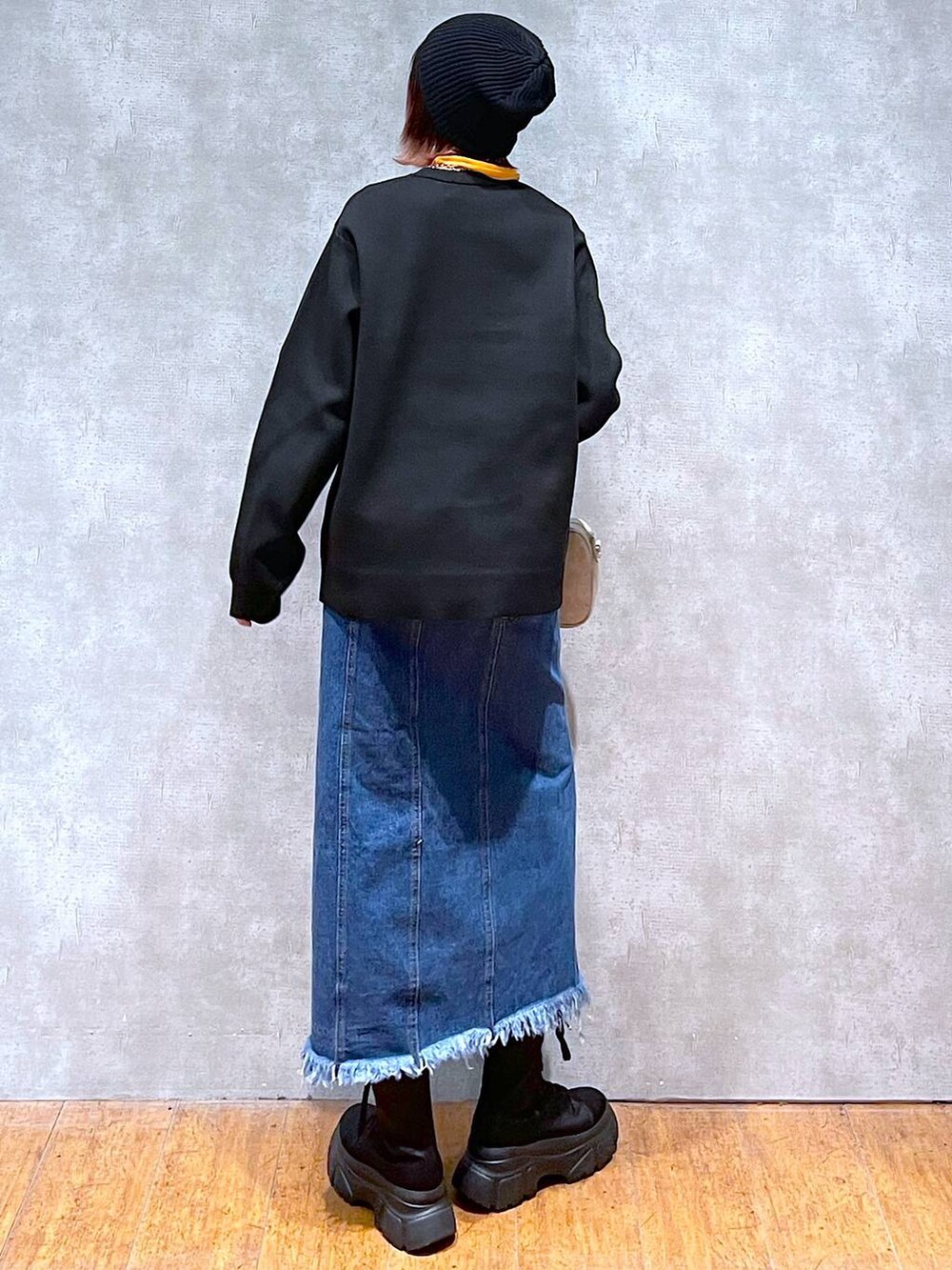 オレンジ系のTシャツ/カットソー、ブラック系のニット/セーター、ベージュ系のボストンバッグを着用したレディースの春コーディネートの5枚目の写真