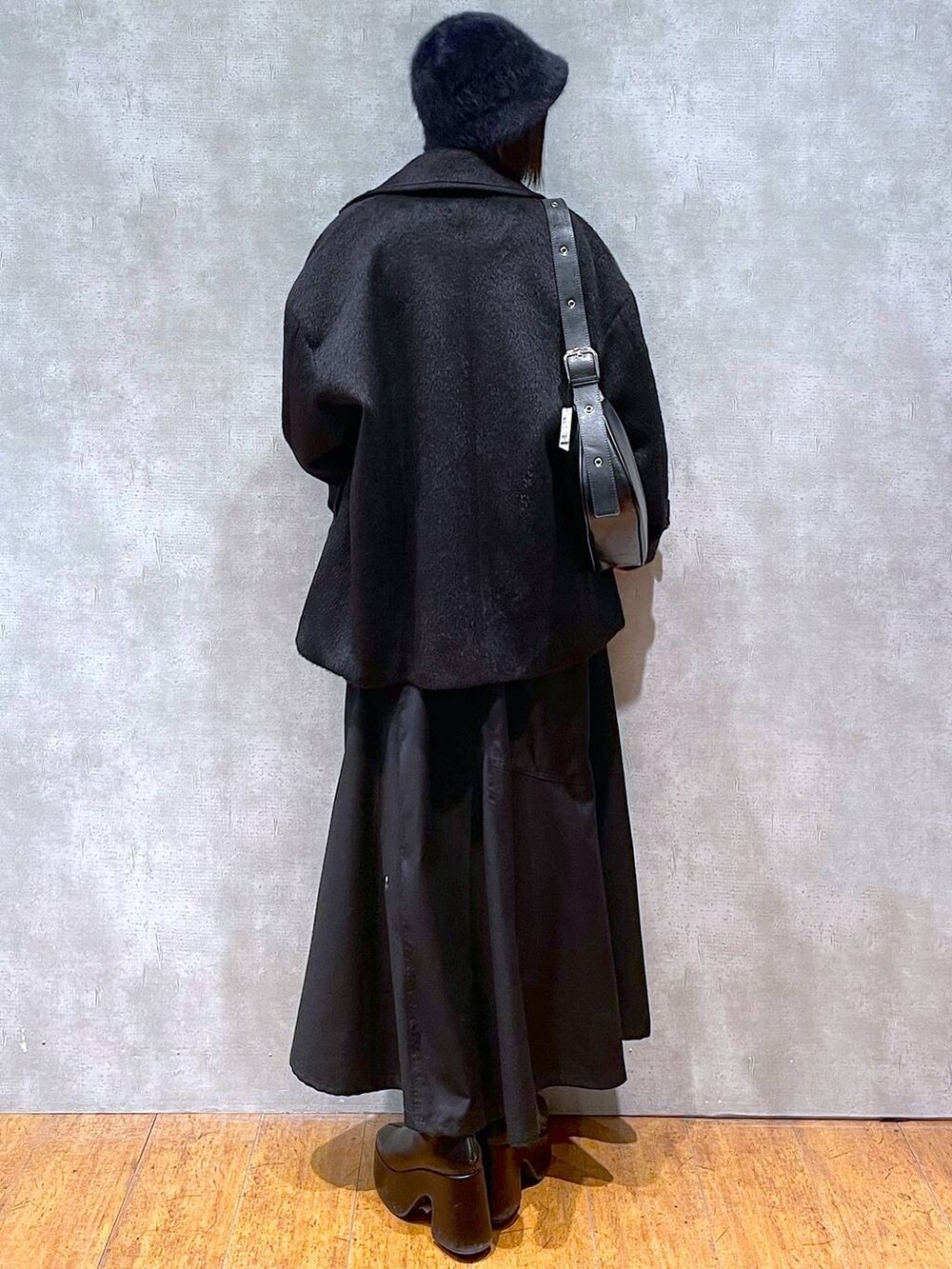 ブラック系のジャンパースカート、ブラック系のブーツ、ブラック系のショルダーバッグを着用したレディースの冬コーディネートの4枚目の写真