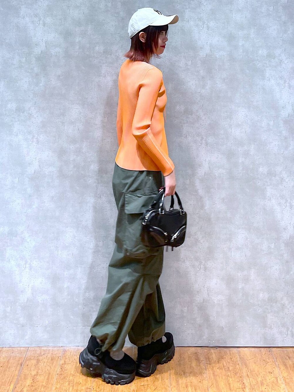 オレンジ系のニット/セーター、ブラック系のタンクトップ、ブラック系のボストンバッグを着用したレディースの春コーディネートの4枚目の写真