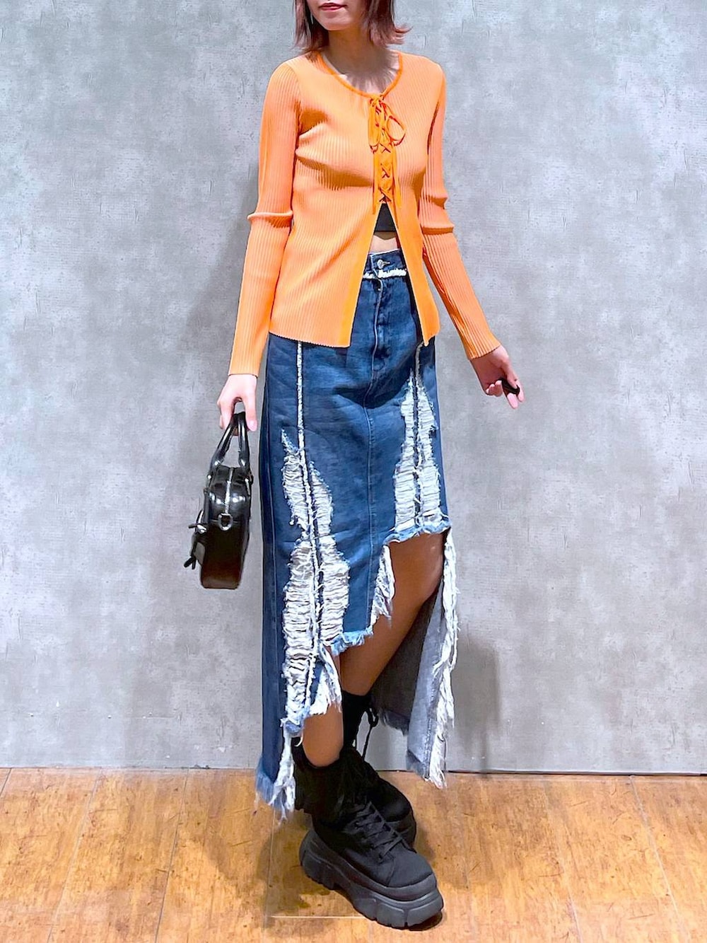 オレンジ系のニット/セーター、ブラック系のキャミソール、ブラック系のボストンバッグを着用したレディースの春コーディネートの3枚目の写真