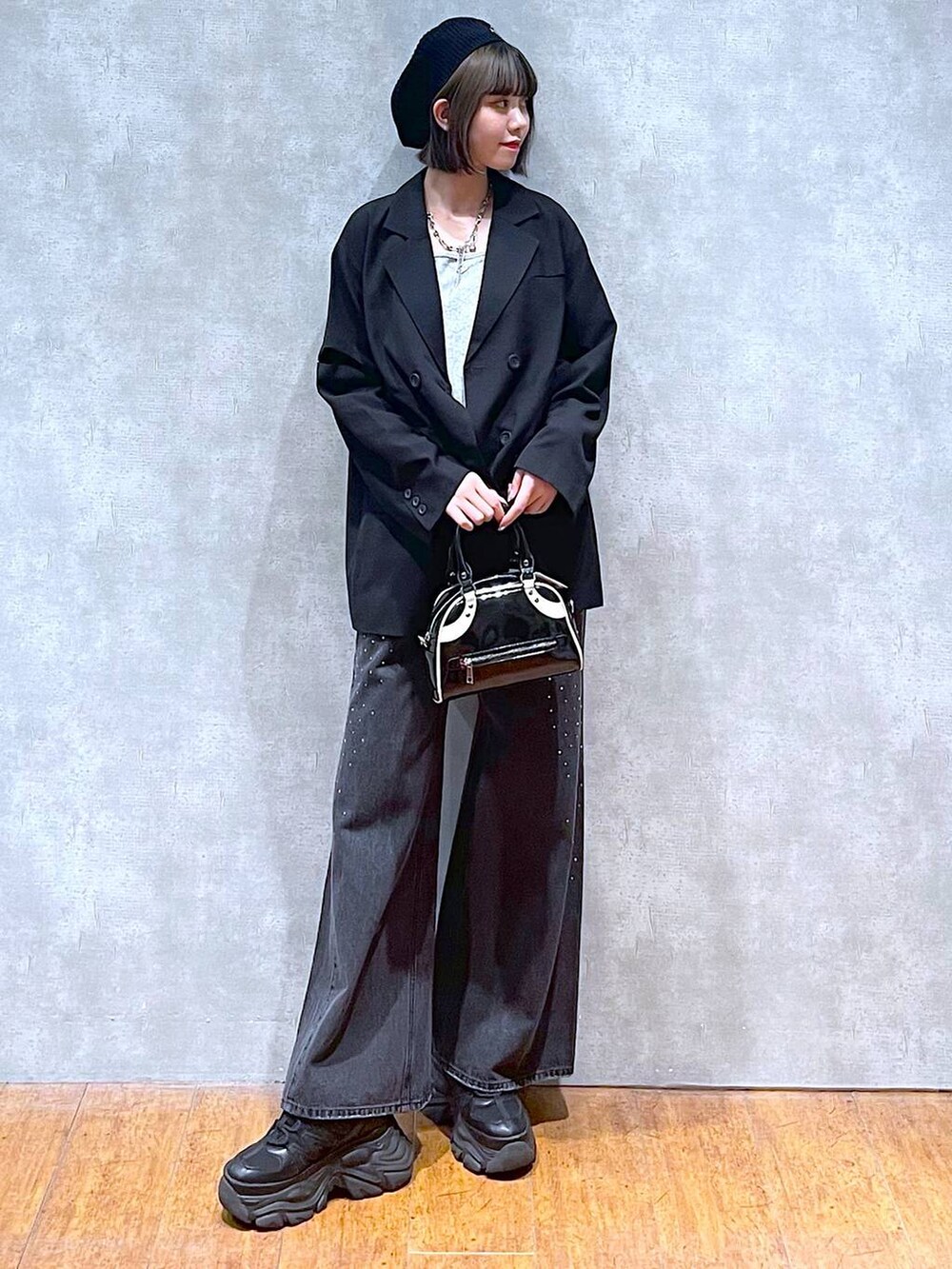 ブラック系のスニーカー、ブラック系のデニムパンツ、ブラック系のショルダーバッグを着用したレディースの秋コーディネートの2枚目の写真