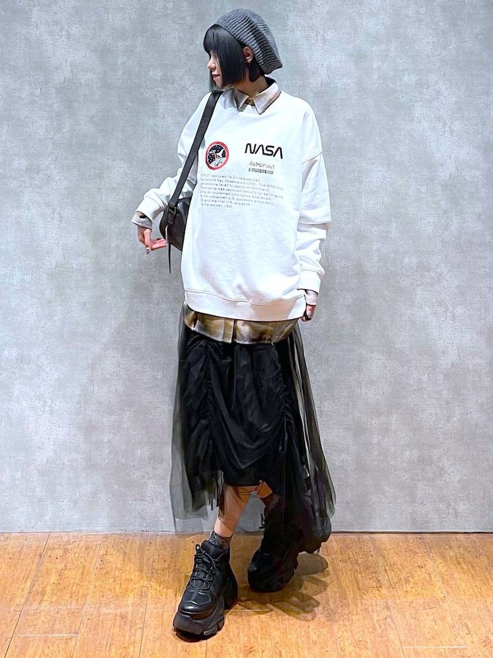 ブラック系のスニーカー、ブラック系のショルダーバッグ、ブラック系のスカートを着用したレディースの秋コーディネートの2枚目の写真