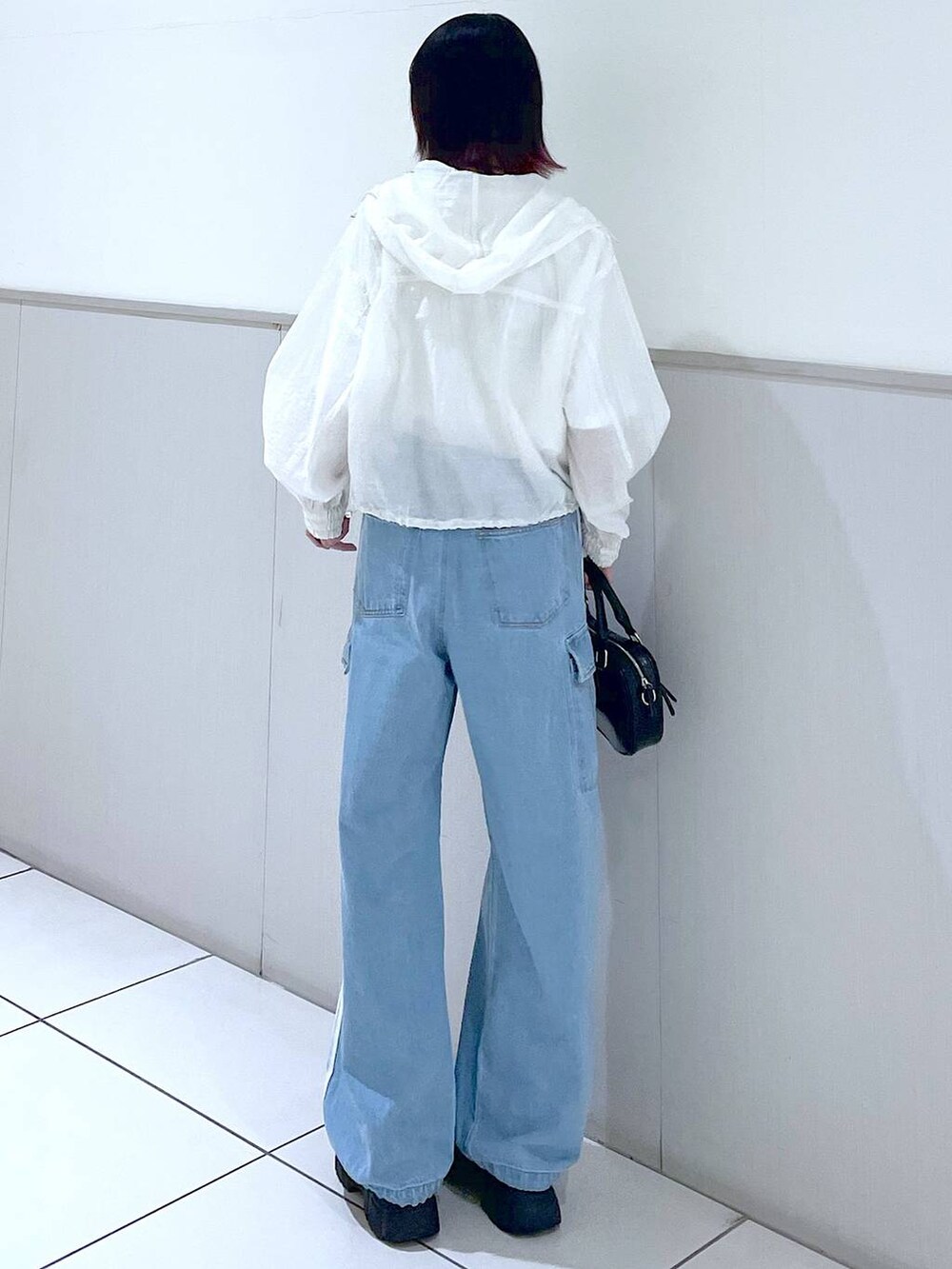 ホワイト系のブルゾン、ブルー系のデニムパンツ、ブラック系のボストンバッグを着用したレディースの春コーディネートの5枚目の写真