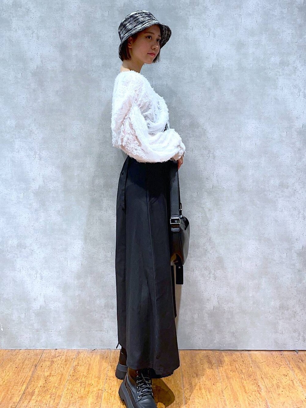 ブラック系のブーツ、ブラック系のショルダーバッグ、ブラック系のジャンパースカートを着用したレディースの夏コーディネートの2枚目の写真