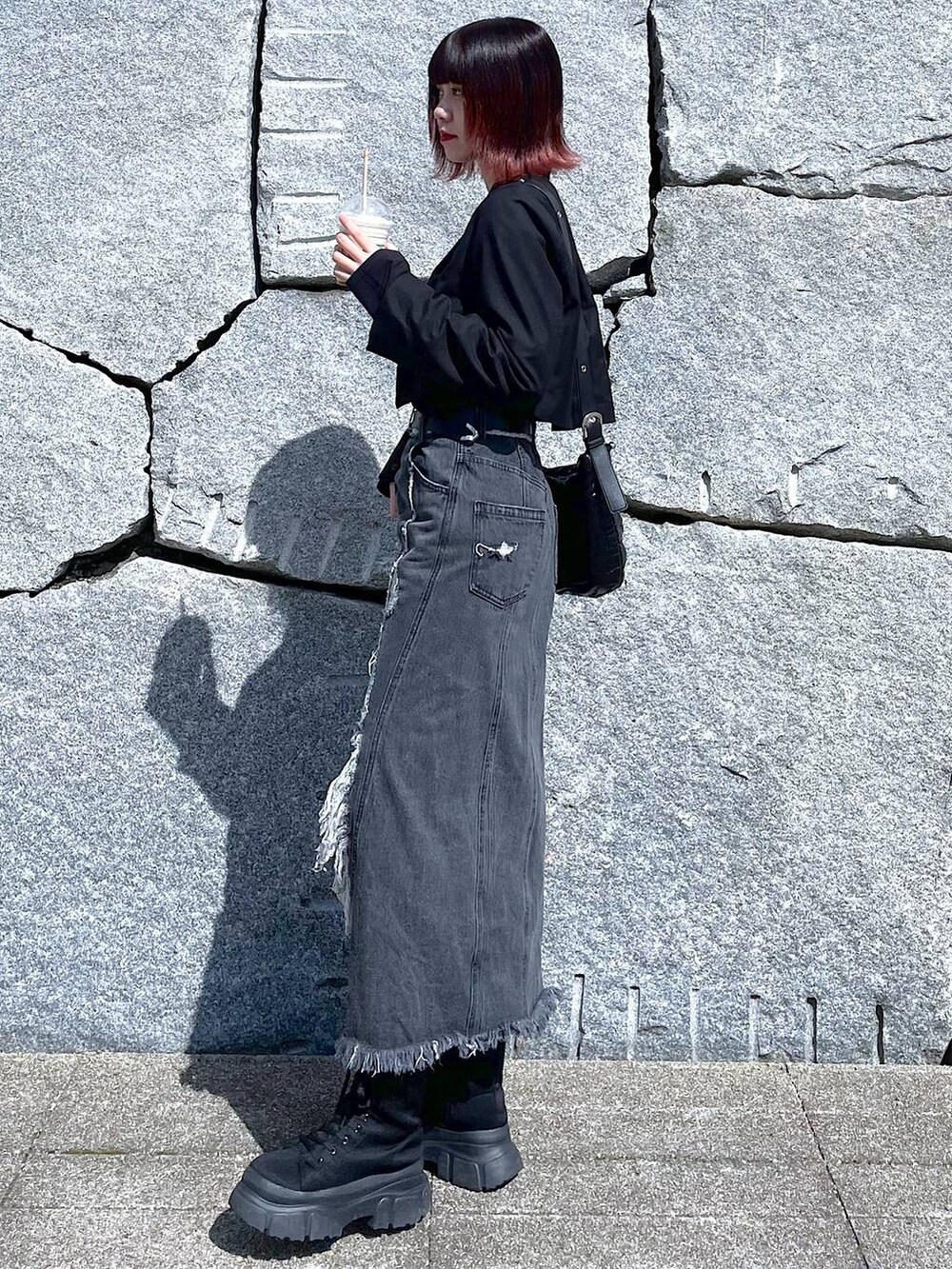 ブラック系のショルダーバッグ、ブラック系のブーツ、ブラック系のデニムスカートを着用したレディースの春コーディネートの4枚目の写真