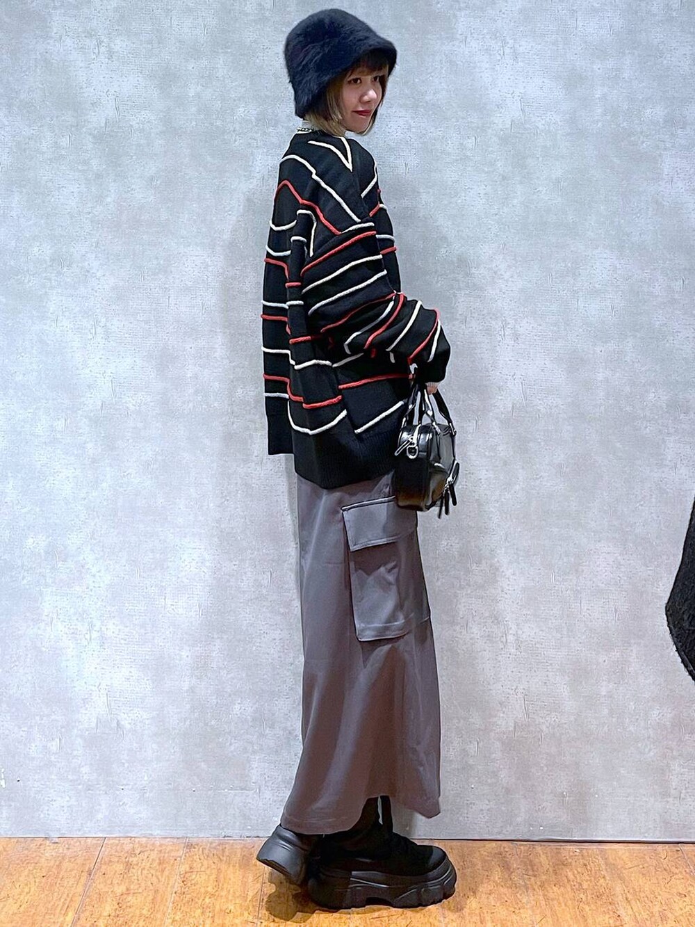 グレー系のスカート、ベージュ系のTシャツ/カットソー、ブラック系のニット/セーターを着用したレディースの冬コーディネートの5枚目の写真