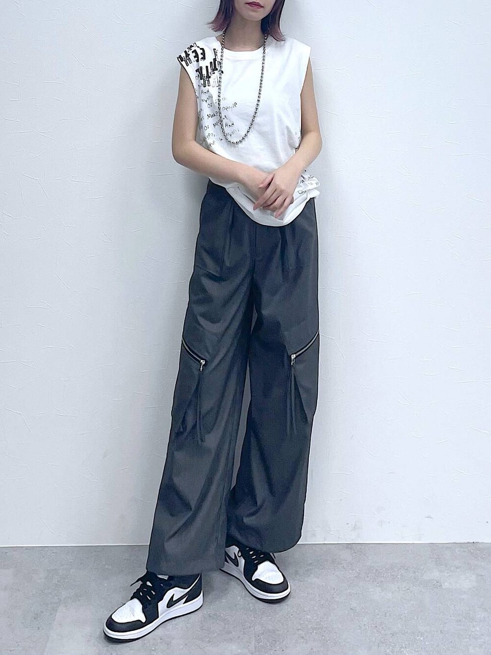 グレー系のスラックス、ホワイト系のTシャツ/カットソー、シルバー系のネックレスを着用したレディースの夏コーディネートの2枚目の写真