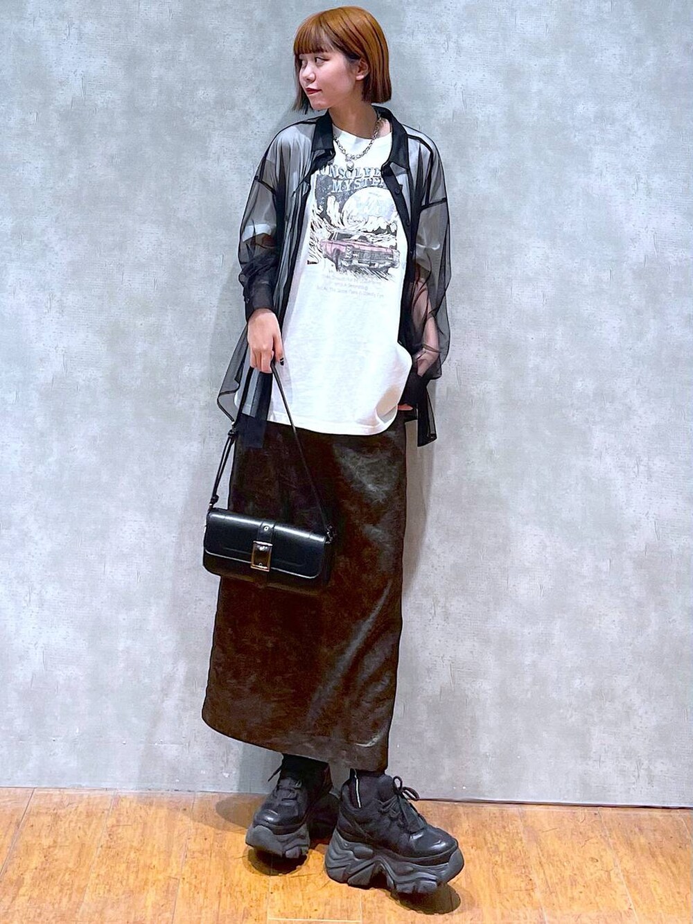 ブラック系のスニーカー、ホワイト系のTシャツ/カットソー、ブラック系のハンドバッグを着用したレディースの夏コーディネートの2枚目の写真