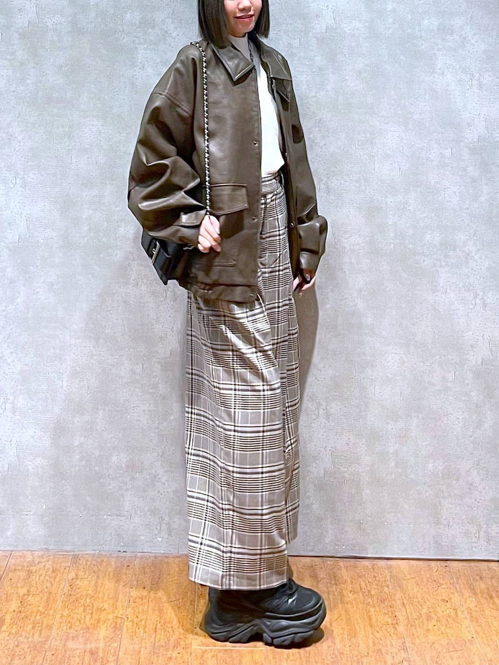 ブラック系のスニーカー、ホワイト系のニット/セーター、ベージュ系のスラックスを着用したレディースの秋コーディネートの3枚目の写真