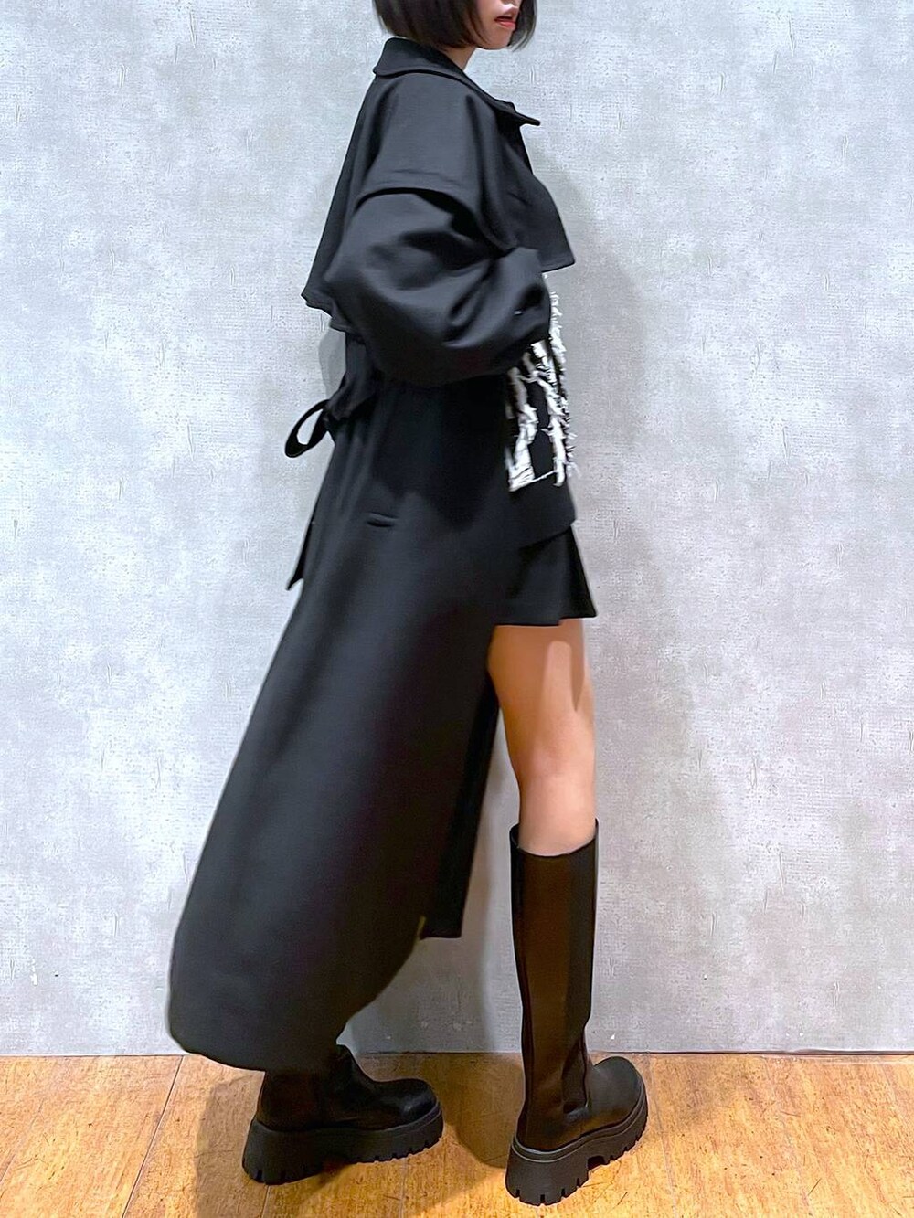 ブラック系のチェスターコート、ブラック系のブーツ、ブラック系のニット/セーターを着用したレディースの冬コーディネートの2枚目の写真