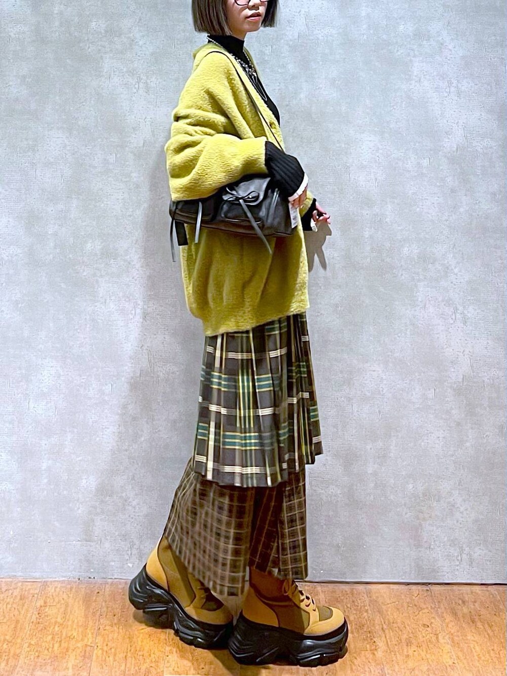 ブラック系のニット/セーター、ブラック系のショルダーバッグ、ブラウン系のブーツを着用したレディースの秋コーディネートの9枚目の写真