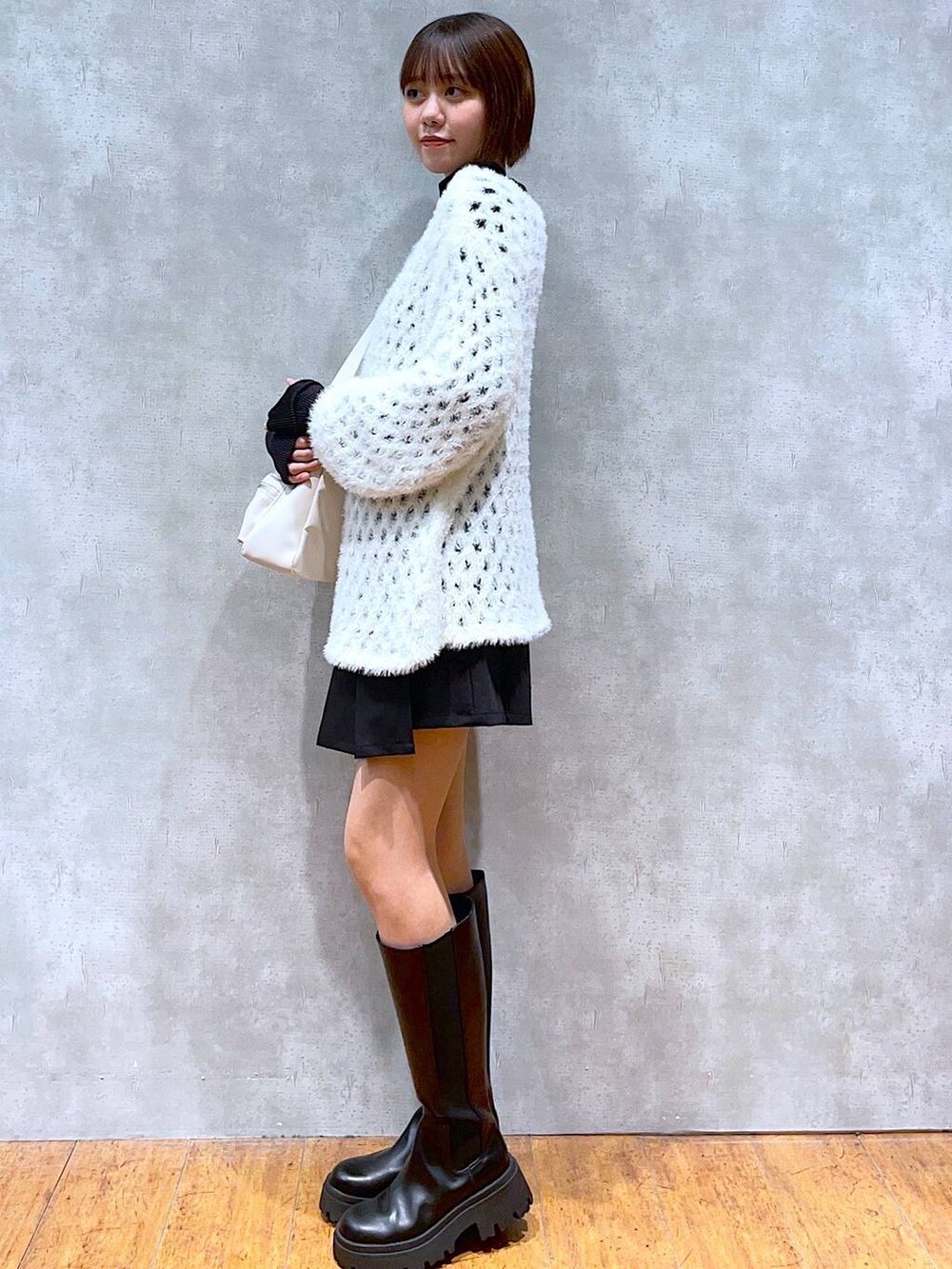 ホワイト系のショルダーバッグ、ブラック系のTシャツ/カットソー、ブラック系のブーツを着用したレディースの秋コーディネートの2枚目の写真