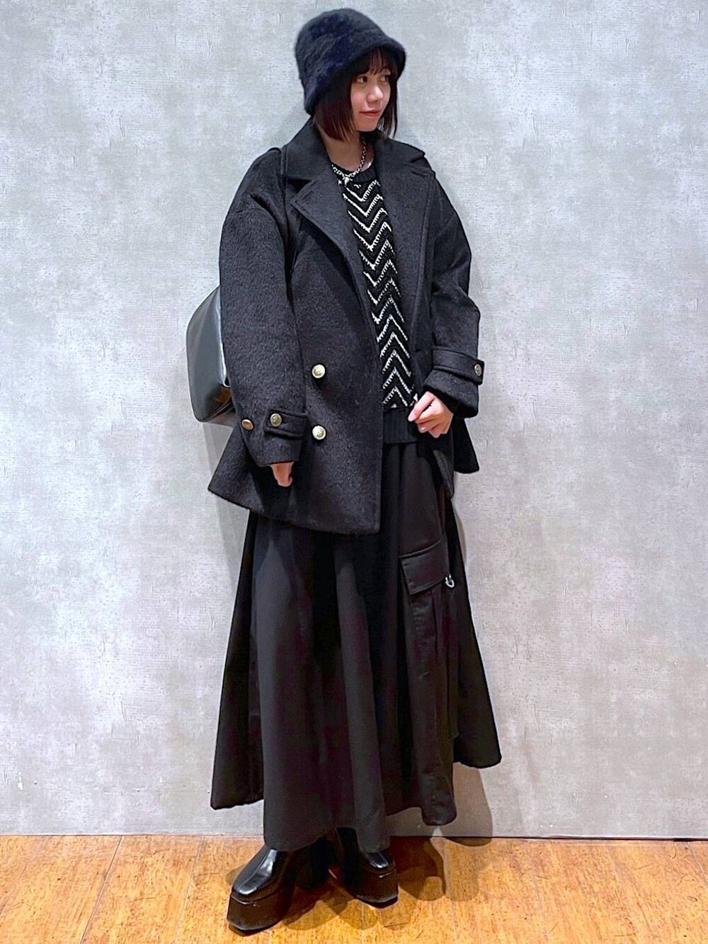 ブラック系のジャンパースカート、ブラック系のブーツ、ブラック系のショルダーバッグを着用したレディースの冬コーディネートの6枚目の写真