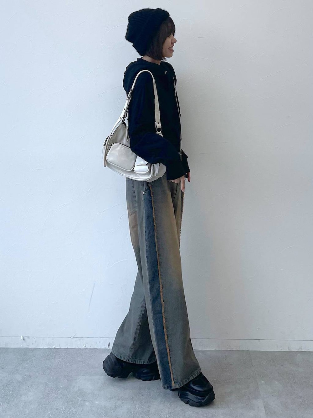 ブラック系のパーカー、ブラック系のスニーカー、ブルー系のデニムパンツを着用したレディースの秋コーディネートの3枚目の写真