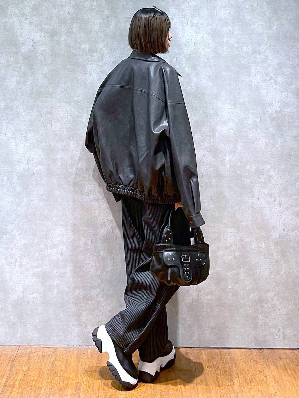 ブラック系のブルゾン、ブラック系のデニムパンツ、ブラック系のハンドバッグを着用したレディースの秋コーディネートの5枚目の写真