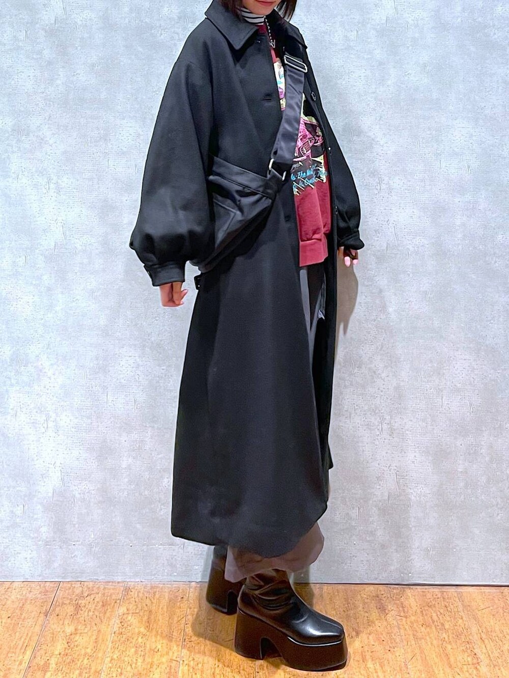 グレー系のスカート、ブラック系のチェスターコート、ブラック系のブーツを着用したレディースの冬コーディネートの3枚目の写真