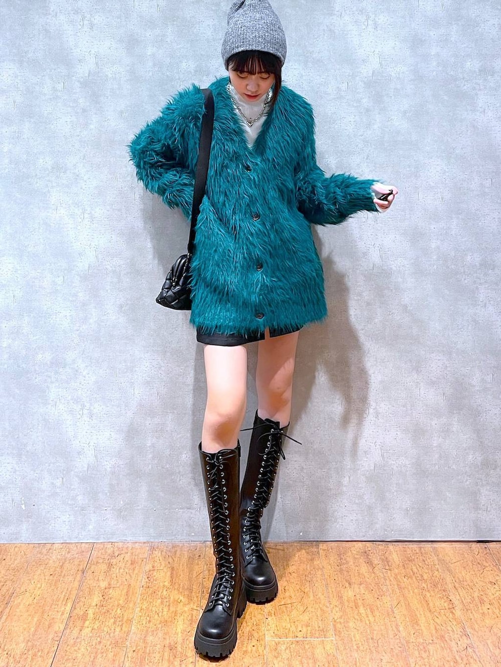 グリーン系のカーディガン/ボレロ、ホワイト系のニット/セーター、ブラック系のブーツを着用したレディースの冬コーディネートの3枚目の写真