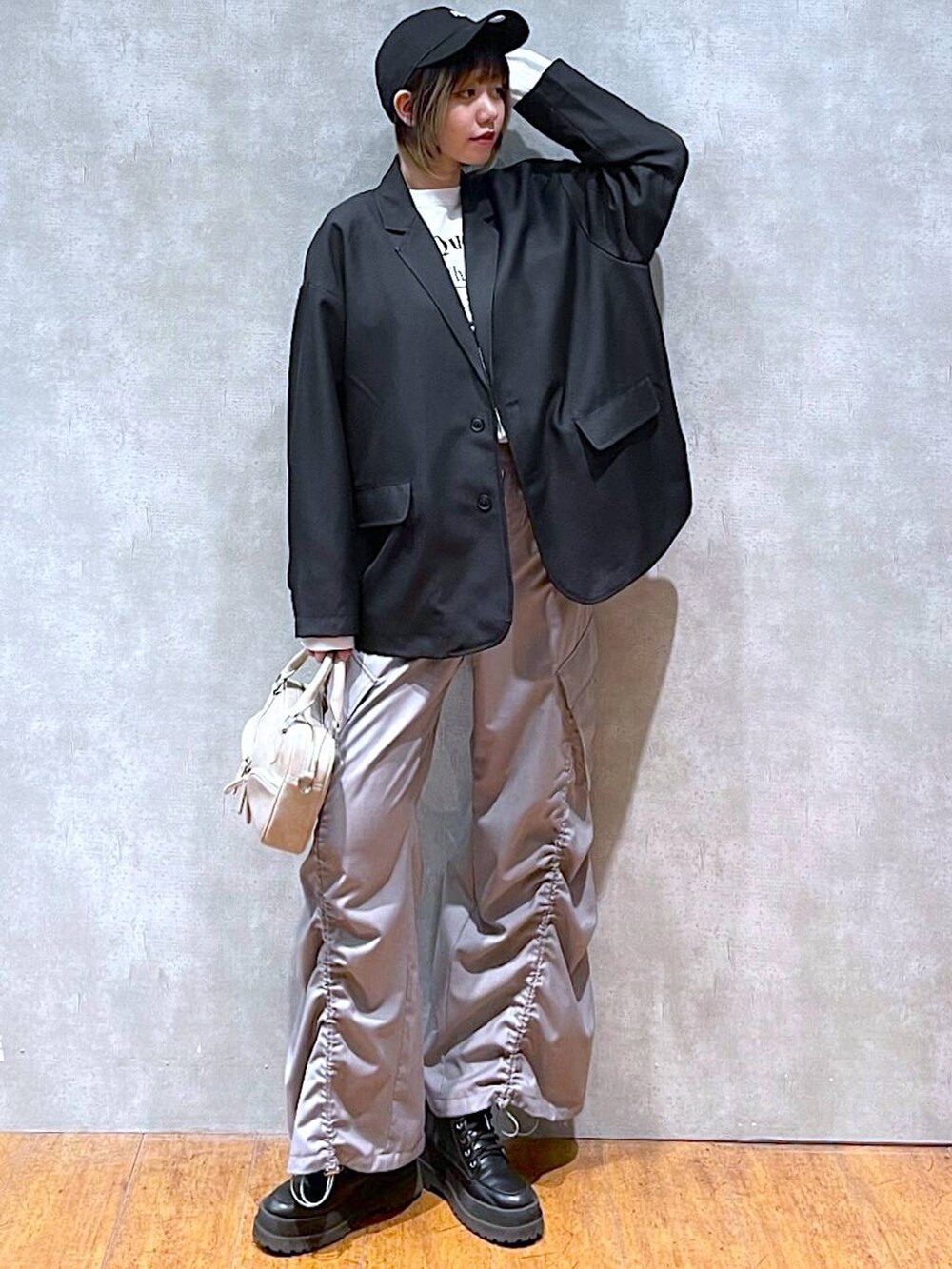 ブラック系のテーラードジャケット、ホワイト系のTシャツ/カットソー、ブラック系のブーツを着用したレディースの冬コーディネートの2枚目の写真