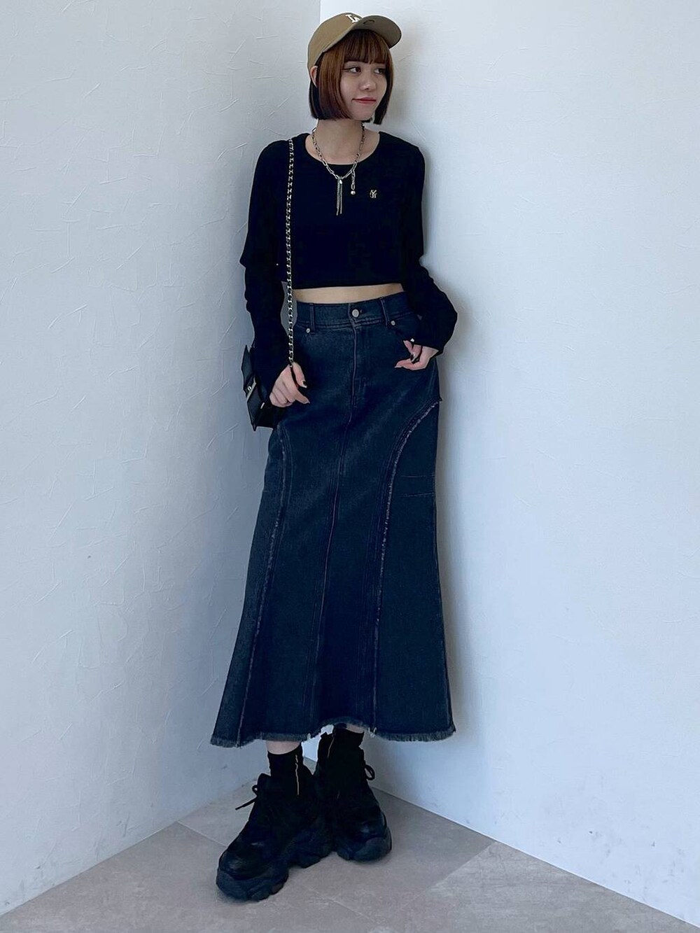 ブラック系のスニーカー、ブラック系のデニムスカート、ブラック系のTシャツ/カットソーを着用したレディースの秋コーディネートの2枚目の写真