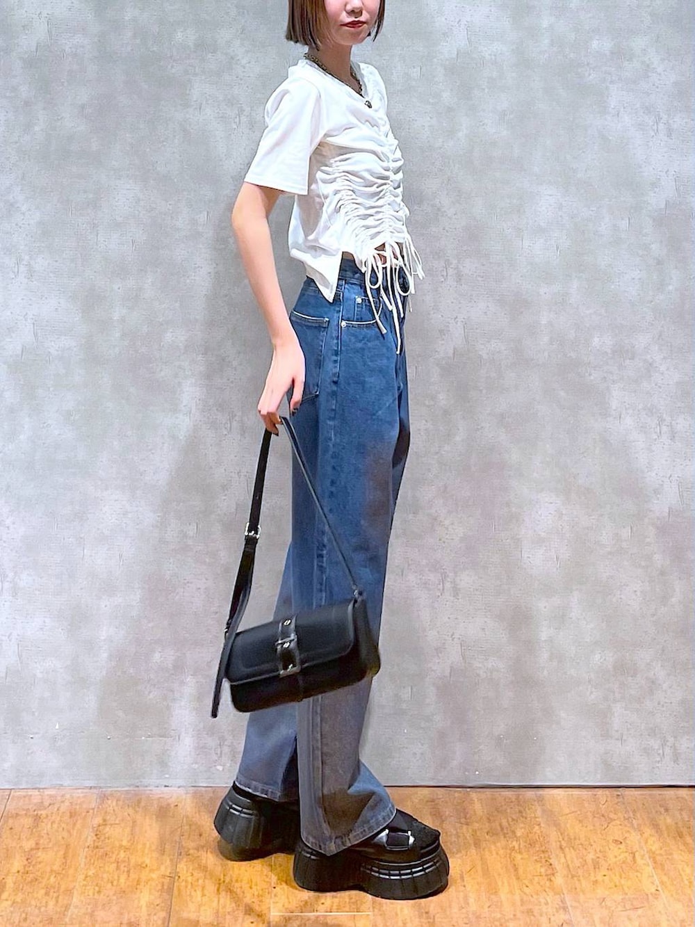 ブラック系のスニーカー、ブラック系のハンドバッグ、ホワイト系のTシャツ/カットソーを着用したレディースの夏コーディネートの4枚目の写真