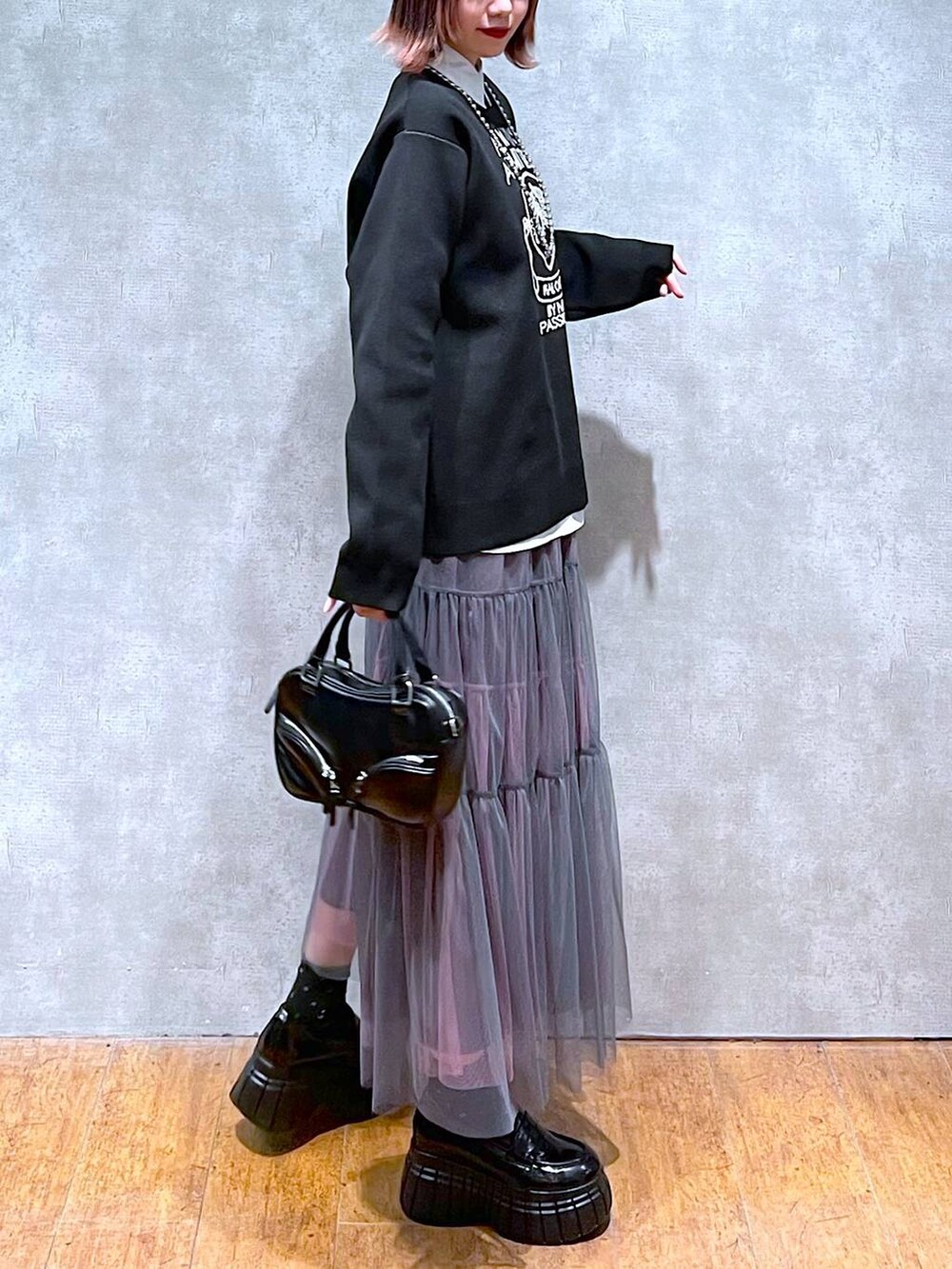 ブラック系のニット/セーター、ホワイト系のシャツ/ブラウス、グレー系のスカートを着用したレディースの春コーディネートの5枚目の写真