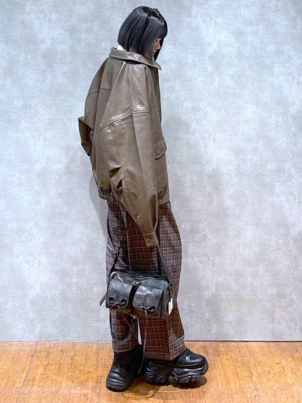 ブラック系のスニーカー、ブラック系のショルダーバッグ、ブラウン系のブルゾンを着用したレディースの秋コーディネートの6枚目の写真