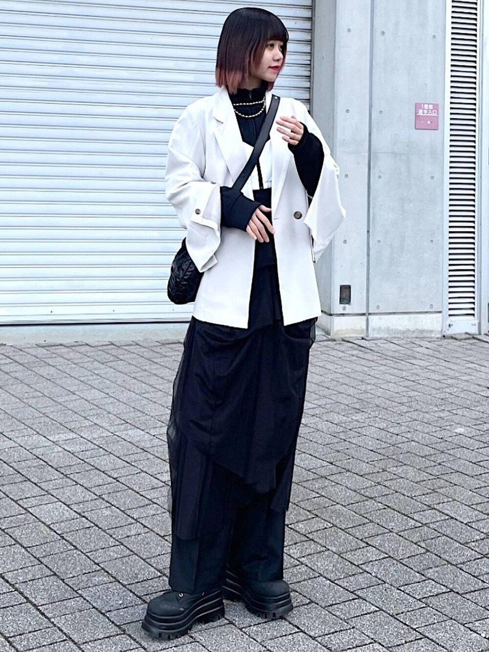 ブラック系のショルダーバッグ、ブラック系のナイロンジャケット、ブラック系のスカートを着用したレディースの春コーディネートの3枚目の写真