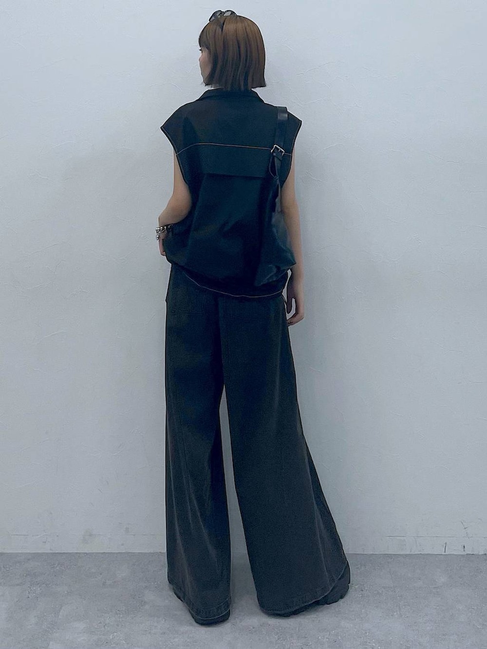 ブラック系のスニーカー、ブラック系のショルダーバッグ、ブラック系のデニムパンツを着用したレディースの夏コーディネートの3枚目の写真