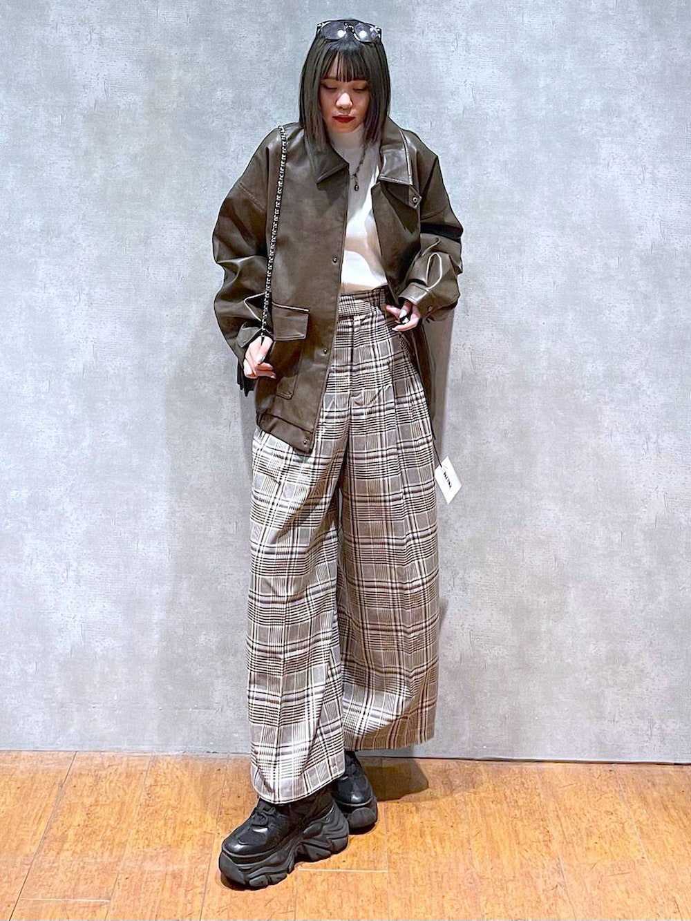 ブラック系のスニーカー、ホワイト系のニット/セーター、ベージュ系のスラックスを着用したレディースの秋コーディネートの7枚目の写真