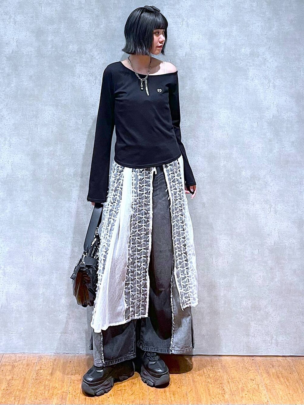 ブラック系のスニーカー、ブラック系のデニムパンツ、ブラック系のショルダーバッグを着用したレディースの夏コーディネートの7枚目の写真