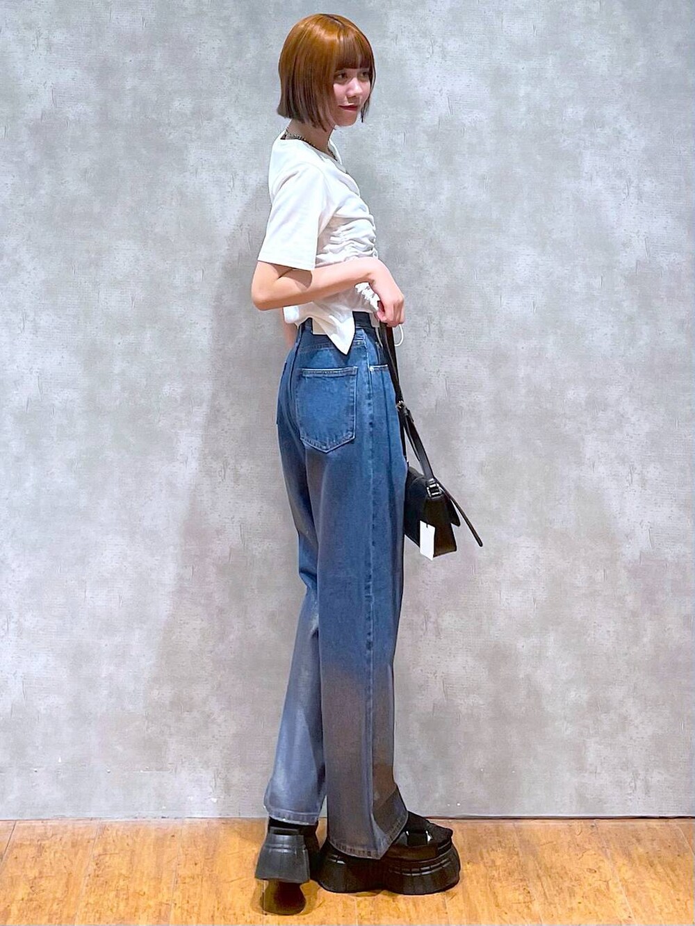 ブラック系のスニーカー、ブラック系のハンドバッグ、ホワイト系のTシャツ/カットソーを着用したレディースの夏コーディネートの3枚目の写真