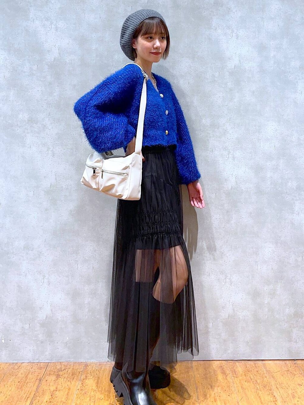 ホワイト系のショルダーバッグ、ブラック系のブーツ、ブルー系のカーディガン/ボレロを着用したレディースの秋コーディネートの2枚目の写真