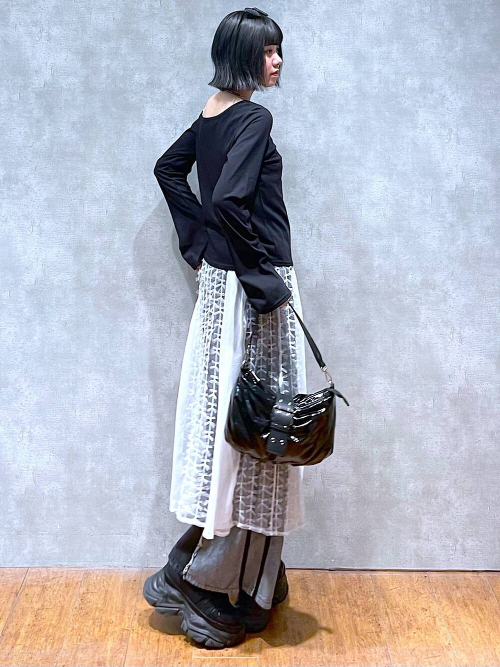 ブラック系のスニーカー、ブラック系のデニムパンツ、ブラック系のショルダーバッグを着用したレディースの夏コーディネートの4枚目の写真